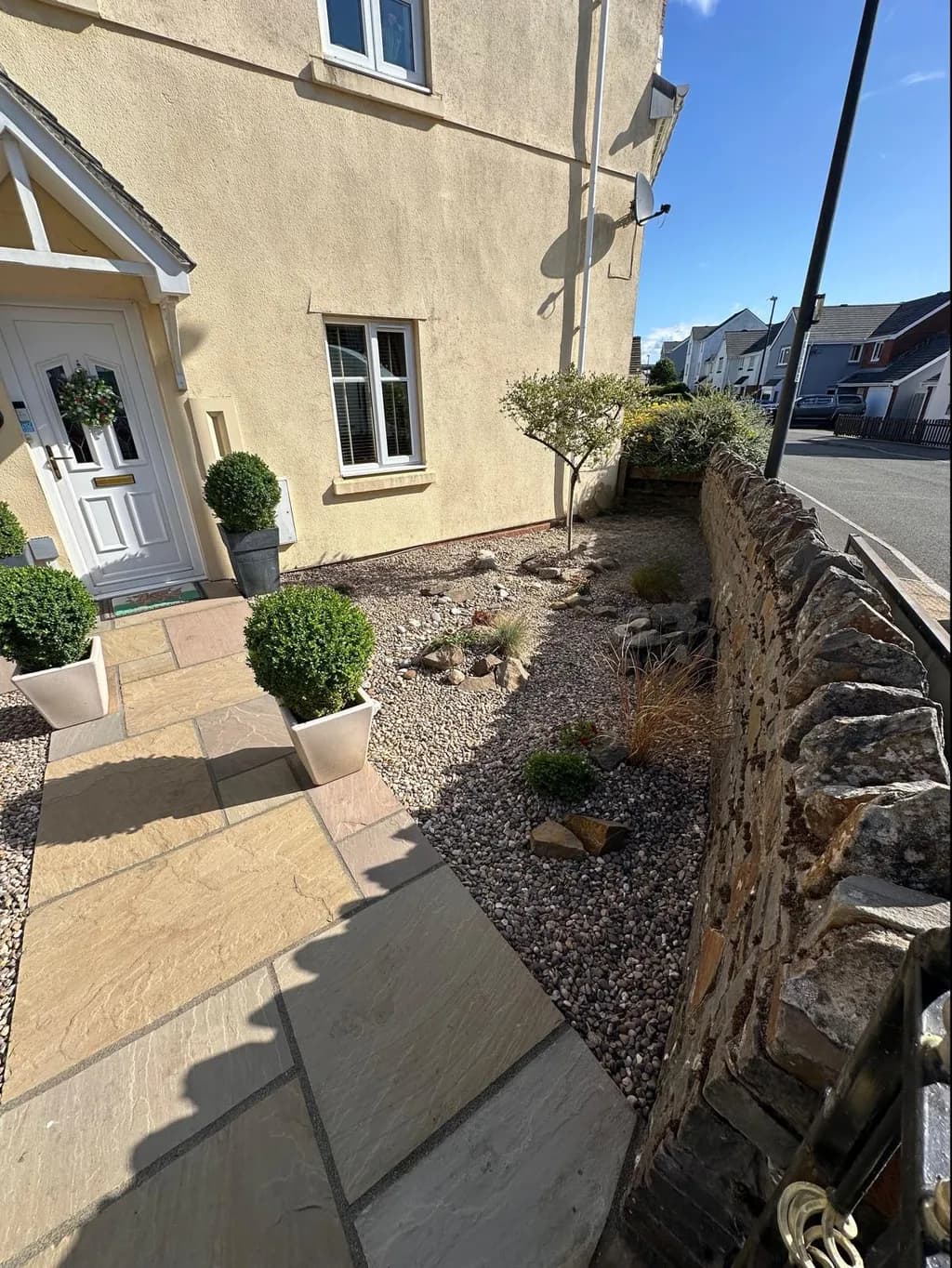 Rockery built with layered stone and planting pockets alongside a natural Indian sandstone walkway in Brynmawr by TJE Landscaping & Building Services Ltd.