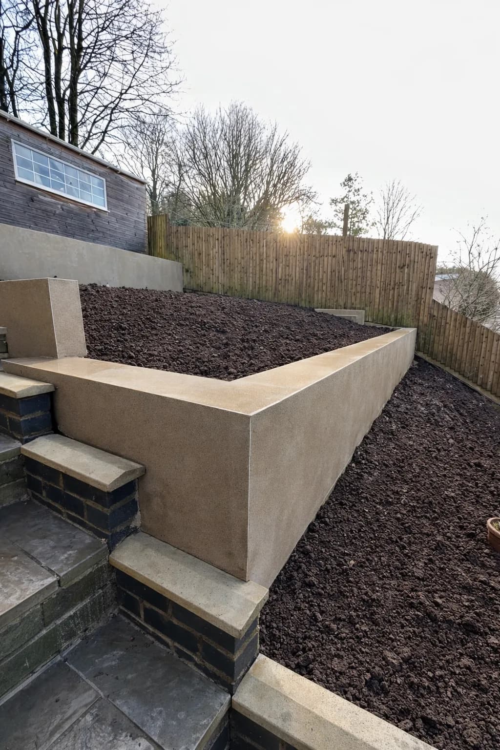Rendered block retaining walls creating smooth, modern tiers in a newly levelled garden built by TJE Landscaping & Building Services Ltd.