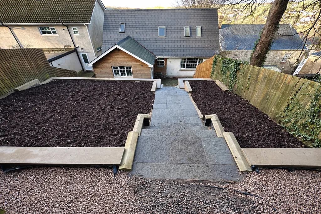 Tiered garden supported by clean, rendered retaining walls, transforming a steep slope into usable outdoor space.