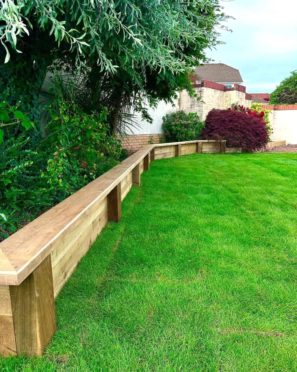 Landscaped multi-level garden in Cwmbran featuring smooth rendered lower retaining walls and timber sleeper upper walls.