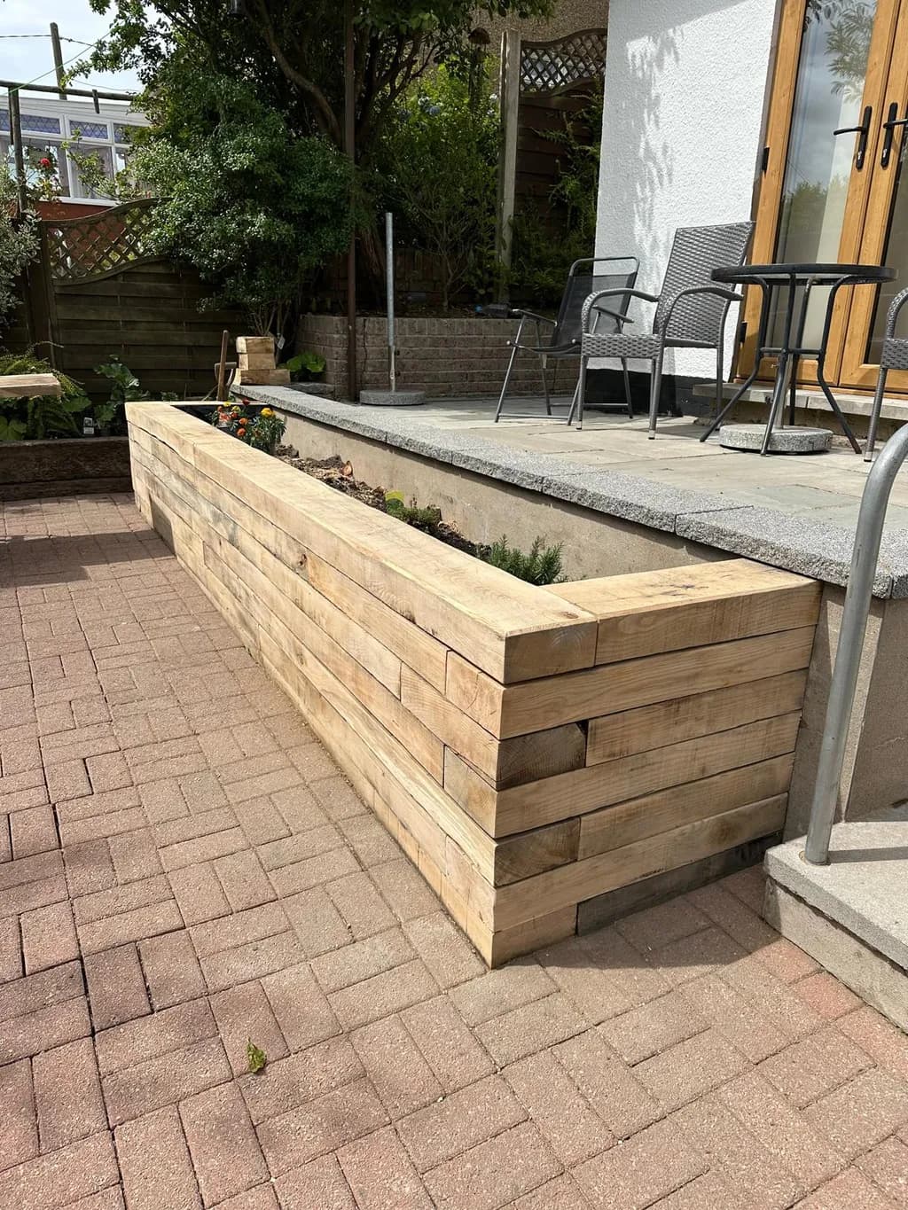 Raised garden bed constructed from solid oak sleepers with a smooth, natural finish.
