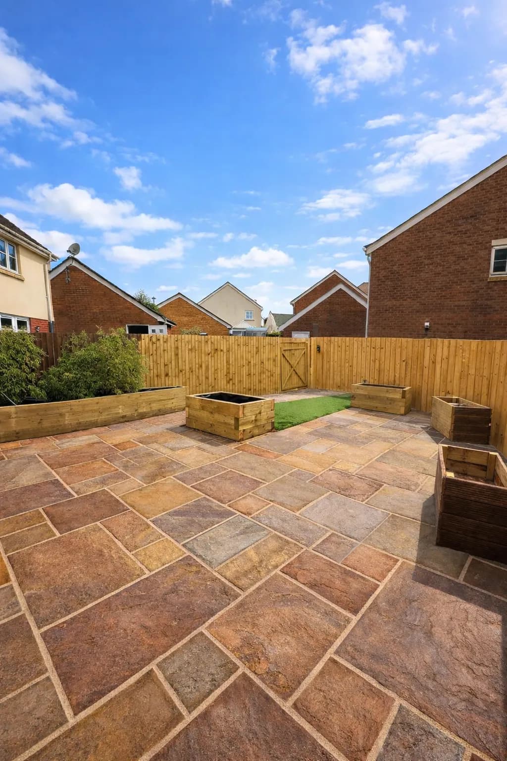 Raised wooden planters positioned on a sandstone patio beside a new garden fence.
