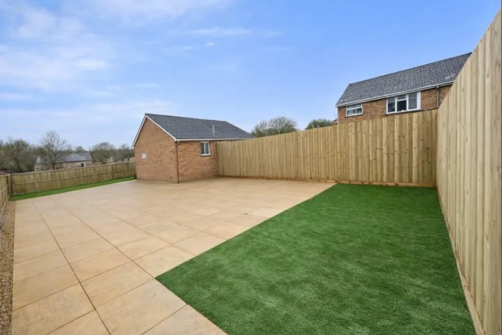 Full garden transformation in Abergavenny with multiple tiers removed to create a level space featuring a new patio, artificial turf, and featheredge fencing.