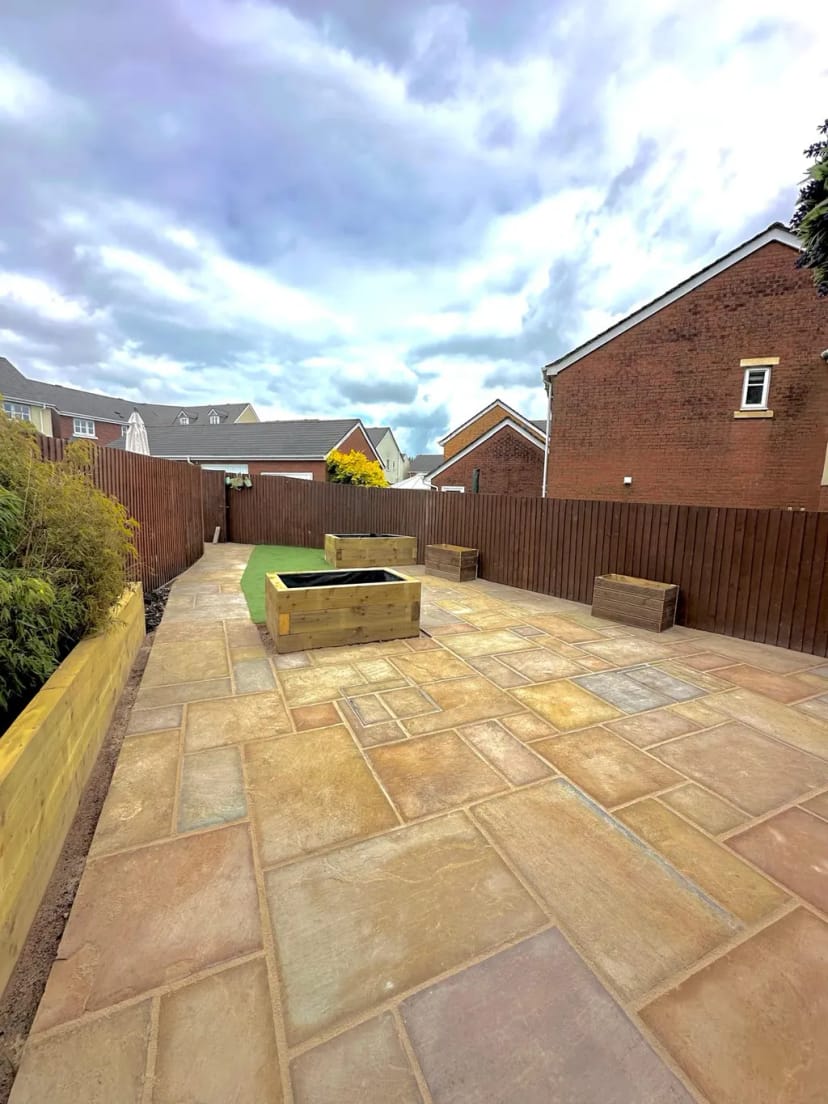 Sandstone patio with raised planters and astroturf