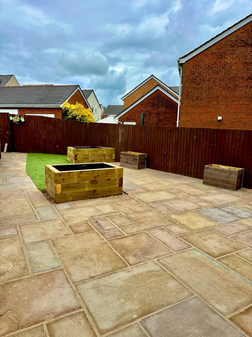 Sandstone patio with raised planters and astroturf