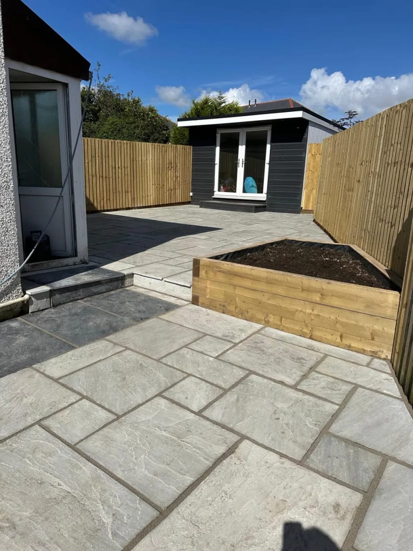 Sandstone patio with black limestone pathway, summerhouse, raised softwood planter and fencing